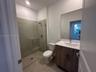 Kitchen featuring wood-finish cabinetry, quartz countertops, a stone-tile backsplash, stainless steel appliances, and large-format tile flooring
