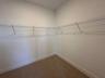 Bedroom featuring vertical wainscoting, dual windows with wall-mounted curtain rods, floating shelving, and neutral-toned wall-to-wall carpeting
