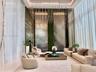 Double-height ceiling, large-scale veined stone wall cladding, floor-to-ceiling windows, custom tiered pendant lighting, and a floor-to-ceiling illumi