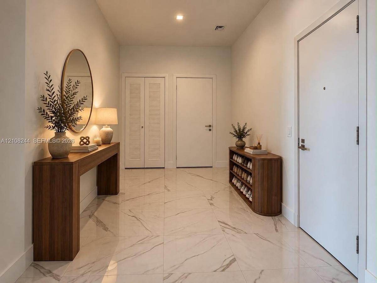 Large-format polished stone flooring with neutral veining, high ceilings with recessed lighting, and crisp white interior doors