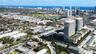 Aerial perspective of high-rise residential towers featuring podium-level swimming pools, landscaped outdoor recreation areas, and proximity to the co