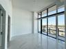 High-ceiling living area featuring large-format polished stone-finish flooring, floor-to-ceiling windows with dark framing, and a private balcony