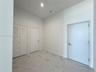 High-ceiling interior featuring stone-finish tile flooring with veining detail, recessed lighting, and white louvered-panel closet doors