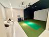 Recreation room featuring integrated projector equipment, a specialized synthetic turf flooring area, high-contrast ceiling paint, and minimalist vert