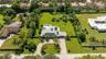 Expansive lot featuring a circular paver driveway, mature landscaping, roof-mounted solar panels, and an in-ground swimming pool