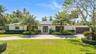 Single-story residence featuring a paved circular driveway, solar panel array, attached multi-car garage, and established landscape