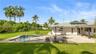 Expansive backyard featuring a stone-paved patio, custom swimming pool with built-in spa, solar panel roof installation, and mature landscaping