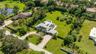 Aerial perspective of an expansive lot featuring a multi-gabled residence, a paved circular driveway, a private in-ground swimming pool, and solar pan