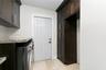 Dark-toned cabinetry featuring stainless steel hardware, stone-finish countertops, tile flooring, and a paneled exterior door