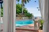 Rectangular swimming pool featuring terracotta tile decking, concrete balustrade fencing, and mature palm trees