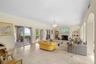 Living area featuring large-format stone tile flooring, three sets of sliding glass doors, a stone-surround fireplace, arched alcoves, and a tiered cr