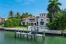 Waterfront residence featuring a private dock, swimming pool, second-story balcony, and terracotta-style roof tiles