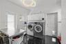 Utility room featuring polished dark tile flooring, white wall-mounted storage cabinetry, a contemporary circular dual-ring chandelier, and a six-pane