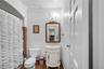 Decorative vanity with carved detailing, stone countertop, gold-toned faucet, wall-mounted light fixture, and framed wall mirror