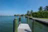 Private waterfront dock with industrial-grade metal decking, timber pilings, and integrated swim ladder, featuring expansive open-water frontage and a