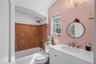 Bathroom featuring a white vanity with an integrated basin, stone tile tub surround, gold-tone hardware, and a crystal chandelier
