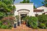 Stucco exterior featuring a decorative stone entryway arch, terra-cotta tile flooring, and terracotta roof accents
