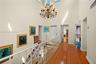 Vaulted ceiling featuring a multi-tiered crystal chandelier, wood-finish flooring, and a decorative metal railing