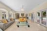 Spacious living area featuring polished stone flooring, arched architectural details, a central crystal chandelier, and two sets of glass-paned double
