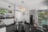 Glossy cabinetry featuring integrated storage, black stone countertops, high-gloss tile flooring, and a rectangular crystal-accented pendant light fix