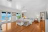 Spacious interior featuring wood-finish flooring, dual sets of French doors, crown molding, a decorative crystal chandelier, and a balcony with water 