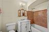 Bathroom featuring a white vanity with carved detailing, stone tile shower surround, brass-finish fixtures, gold-toned ornamental mirror, and a crysta