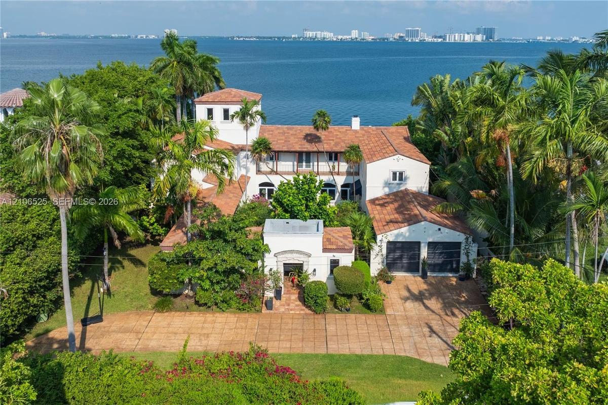 Mediterranean-style estate featuring a terracotta tile roof, multi-story tower architecture, a paved motor court, and an attached two-car garage, situ