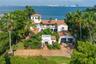 Mediterranean-style estate featuring a terracotta tile roof, multi-story tower architecture, a paved motor court, and an attached two-car garage, situ