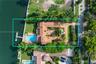 Waterfront estate featuring a private dock, rectangular swimming pool, terracotta tile roof, brick-paved courtyard, and mature landscaping