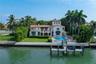 Waterfront residence featuring a private dock, swimming pool, tiled roof, and expansive lawn
