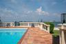 In-ground swimming pool with tile border, terracotta tile patio, and concrete balustrade railing overlooking the water