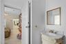 Custom vanity with an integrated stone countertop, oval undermount sink, brass finish widespread faucet, and matching brass-rimmed wall mirror