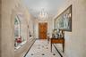 Entryway featuring natural stone block walls, arched window alcoves, tile flooring with decorative stone insets, a crystal chandelier, and a solid woo
