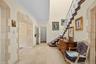Foyer featuring high ceilings, stone-trimmed arched entryways, large-format tile flooring, and a staircase with ornate metal railings