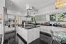Modern kitchen featuring high-gloss cabinetry, a central island with a stone-finish countertop, stainless steel double wall ovens, a ceiling-mounted s