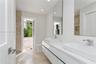 Modern floating vanity with dual rectangular vessel sinks, quartz countertops, and polished chrome faucets, complemented by wall-to-wall mirrors and s