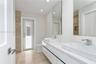 Floating double vanity with rectangular vessel sinks, quartz countertop, chrome faucets, and large-format tile flooring