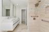 Floating vanity with dual rectangular vessel sinks, wall-mounted rectangular mirrors, walk-in shower with stone-finish tile surround, built-in shower 