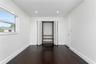 Interior room featuring wood-finish flooring, recessed lighting, white walls, louvered closet doors with built-in shelving, and a dual-pane window