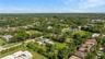Aerial perspective featuring a sprawling lot with an inground pool, expansive lawn, mature palms, and paved driveway access
