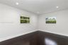 Interior room featuring dark wood-finish flooring, crisp white walls, and recessed ceiling lighting