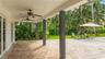 Covered patio featuring concrete paver flooring, dual ceiling fans, and dark-stained structural support pillars