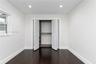 Neutral interior featuring dark wood-finish flooring, recessed lighting, and a closet with white louvered bi-fold doors and built-in shelving