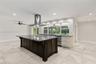 Kitchen featuring a large central island with dark cabinetry, stone-finish countertops, stainless steel professional-grade range hood, recessed lighti