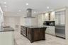 Kitchen featuring a central island with a built-in oven, stone-finish countertops, stainless steel appliances, recessed ceiling lighting, and tile flo