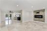 Living area featuring large-format tile flooring, recessed lighting, and a floor-to-ceiling stone-veneer accent wall with an integrated electric firep