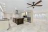 Kitchen featuring a center island with dark wood-finish cabinetry, stainless steel appliances, a stainless steel range hood, stone countertops, and ti