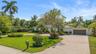 Single-story exterior featuring a paver driveway, an attached garage, and manicured landscaping with mature palm trees