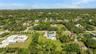 Aerial perspective featuring an expansive lot, established tropical landscaping, mature canopy trees, and an integrated swimming pool