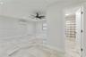 Large-format tile flooring, multi-blade ceiling fan, recessed lighting, wall-mounted air conditioning unit, and dual-pane window